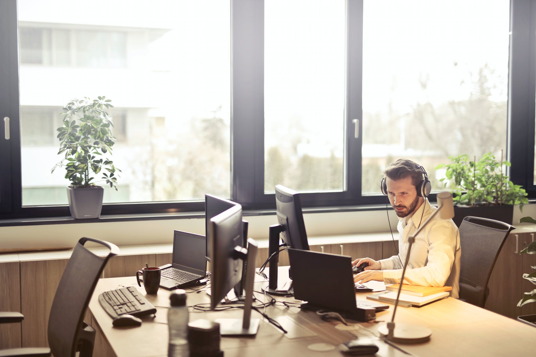Man wearing headphones working on laptop at desk in empty office