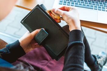 Person sat in front of laptop taking bank card out of purse